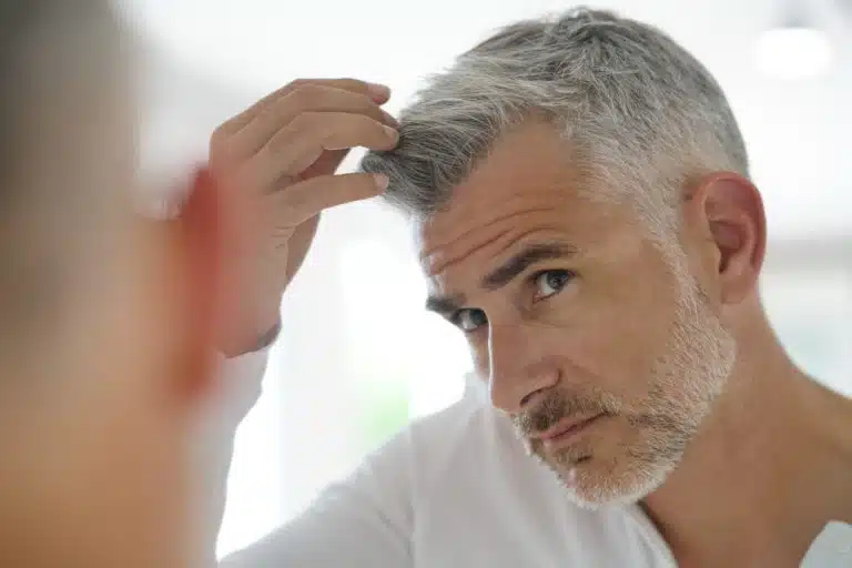 40-year-old man checking hair in front of mirror

